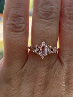 a woman's hand with a pink diamond ring on it