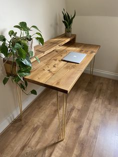 a wooden desk with a laptop on top of it next to a potted plant