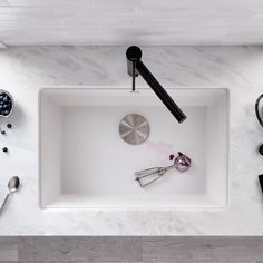 an overhead view of kitchen utensils in a white square sink with marble countertop