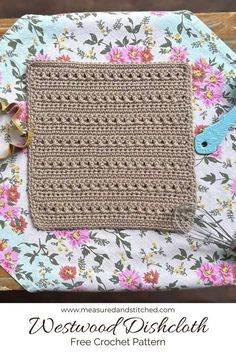 a crocheted dishcloth is sitting on top of a flowered table cloth