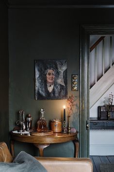 a living room filled with furniture and a painting on the wall next to a table