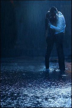 a man standing in the rain with his head on his hands while holding an umbrella