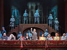 a group of people sitting at a table in front of a stage with statues on it