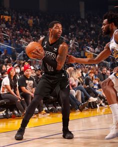 two basketball players in action on the court with fans watching from the bleachers