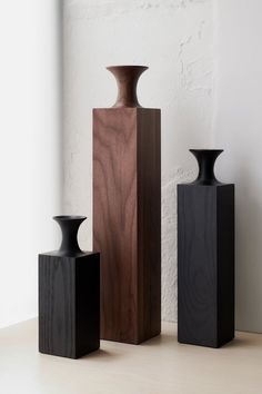 three black vases sitting next to each other on a table