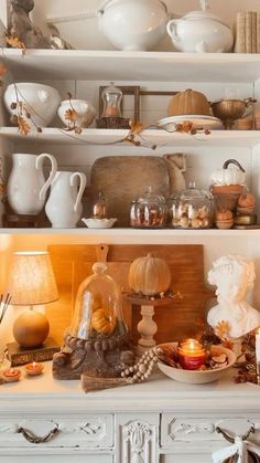 a white hutch filled with lots of dishes and candles on top of it's shelves