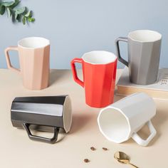 three different colored coffee mugs sitting next to each other on top of a table