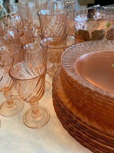 a table topped with lots of glassware and plates on top of a white table cloth