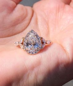 a close up of a person's hand holding an engagement ring