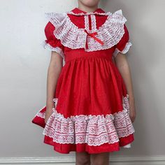 "Frilly full circle skirt red dress with white lace trim that is perfect for twirling. The red fabric has a shiny tiny polka dot weave. The skirt is lined with a white layer. It buttons up the back and there is an attached tie belt.  Brand - Mini World Content - 80% Polyester 20% Rayon  Size - Labeled Size 4 but it fit my average size 5 year old with a little room to grow so please check all measurements to insure fit Shoulders - 10\" across Chest - 12\" pit to pit  Sleeves - 5.75\" from shoulder seam Waist - 11.5\" across Length - 22\" (9.75\" bodice, 12.25\" skirt) Condition - I don't see any flaws" Red Vintage Dress With Lace Trim, Vintage Red Dress With Lace Trim, Red Vintage Costume Dress, Red Vintage Victorian Dress With Ruffles, Retro Red Ruffled Dress, Retro Red Dress With Ruffles, Retro Red Dress For Costume Party, Frilly Dress, Mini World