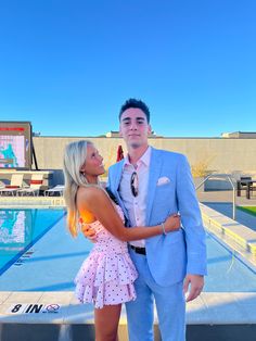 a man and woman standing next to each other in front of a swimming pool