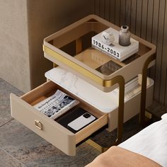 an open drawer on a nightstand next to a bed with a phone and other items