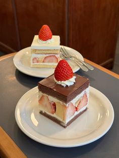 two pieces of cake with strawberries on top are sitting on the table next to each other