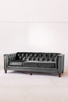 a black leather couch sitting on top of a white floor next to a wooden table