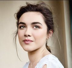 a close up of a person wearing a white shirt and looking at the camera with a serious look on her face