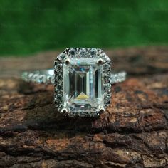 an emerald cut diamond ring on top of a piece of wood