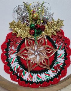 a crocheted christmas ornament with gold, red and green decorations on it