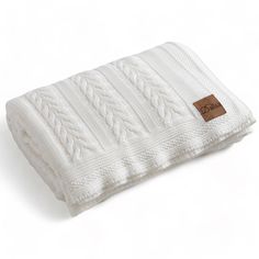 a white knitted blanket with a brown tag on it's front and back