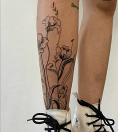 a woman's legs with tattoos on them and white shoes in front of her