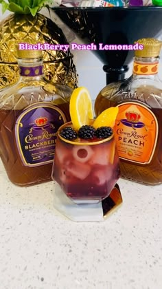 two bottles of blackberry peach lemonade next to a glass filled with ice and blackberries