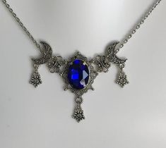 This is a new handmade necklace. It is made with antiqued silver plated filigrees, accented with a high quality DARK BLUE glass rhinestone. Decorated portion is 2 1/2" wide and 1 3/4" tall in the center. Necklace is adjustable 15-18" with a lobster clasp and chain extender. If you would like a different length, please send us a message.