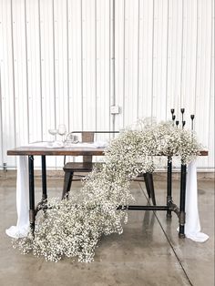 a table with flowers and candles on it in front of a white wall that says love