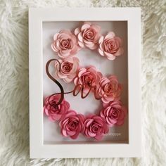 pink paper flowers in a white frame on a furry surface with the word love spelled out