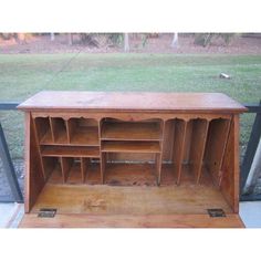 an old wooden cabinet sitting in front of a glass window with grass and trees behind it