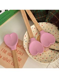 two pink heart shaped spoons sitting on top of a plate