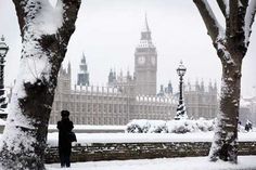 the big ben clock tower towering over the city of london covered in snow