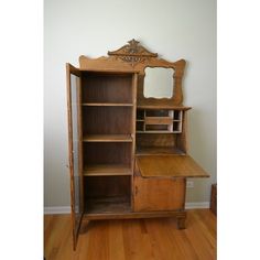 an old fashioned wooden desk with mirror on top and shelf below it in a room