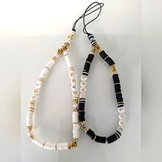 two black and white beaded necklaces with gold accents on each strand, one in the shape of a tear