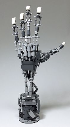 a robot hand made out of legos on a gray background with white lights in the middle