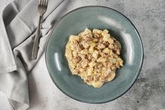 a blue plate topped with macaroni and cheese next to a knife and fork