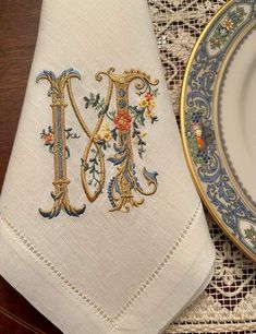 an embroidered monogrammed napkin sits next to a plate