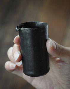 a person holding a black cup in their hand