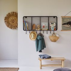 there is a coat rack with hats and books on it next to a wooden bench