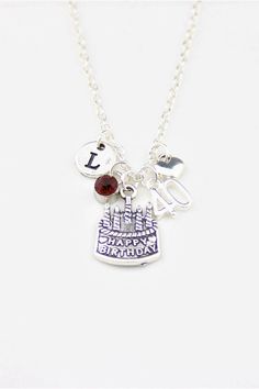 a necklace with charms on it that says happy birthday and is hanging from a silver ball chain