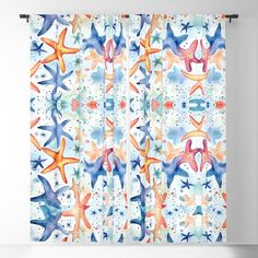 a curtain with starfishs on it in blue, orange and pink colors hanging from the side