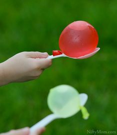 a hand holding a red and white plastic spoon