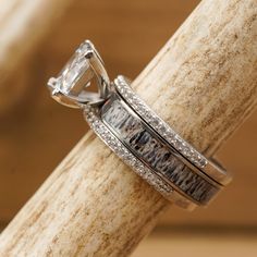 a close up of a wedding ring on top of a piece of wood with diamonds