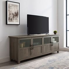 a flat screen tv sitting on top of a wooden entertainment center next to a window