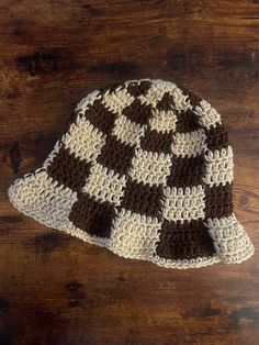 a brown and white crocheted hat sitting on top of a wooden table next to a pair of scissors