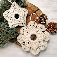 three crocheted ornaments sitting on top of a piece of wood next to pine cones