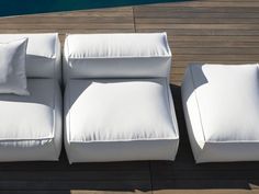 three white couches sitting on top of a wooden floor next to a swimming pool