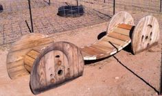 an upside down wooden bench sitting in the middle of a dirt field next to a wire fence