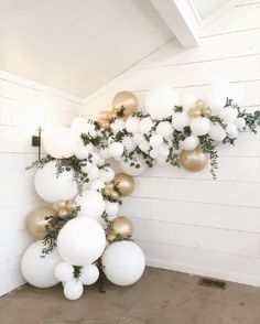 some white and gold balloons are hanging on the wall