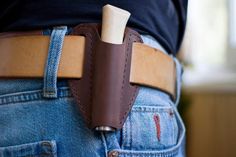 a person wearing a brown leather belt with a white wooden object in the back pocket