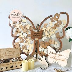 a wooden butterfly decoration with two candles on the table next to it and some other items