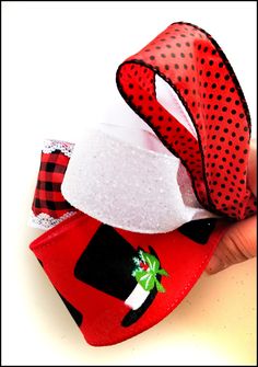 a hand holding two red and black hair bows on top of each other with polka dots